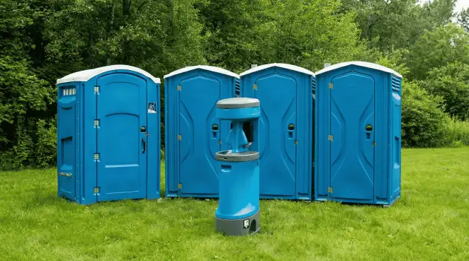 Four blue portable toilets and a matching hand washing station on grass near trees, a common sight at local outdoor events in Richmond, VA